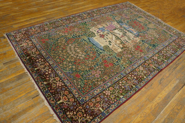 Detailed rug with a green floral field, burgundy border, and cream pictorial panel on distressed wood floorboards.