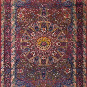 Detailed traditional rug with a deep red center field, a navy border, and colorful floral ornamentation.