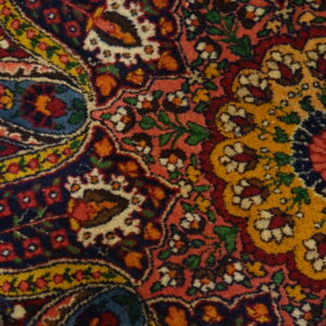 Intricate traditional rug pattern featuring colorful red, navy, gold, and pink floral and boteh motifs.