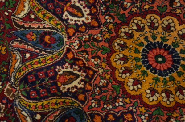 Intricate traditional rug pattern featuring colorful red, navy, gold, and pink floral and boteh motifs.