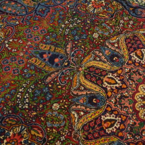 Detailed view of a low-pile rug featuring complex red, blue, green, and gold botanical and curvilinear designs.