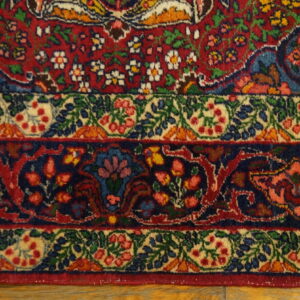 Red, navy, and cream rug borders display intricate floral patterns on a visible wood floor.