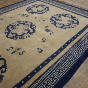 Low-pile beige rug with dark blue stylized dragon patterns and a geometric border on distressed wood.