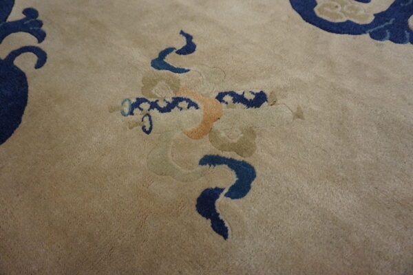 Detail of a plush beige rug with stylized blue, orange, and sage scrollwork motifs.