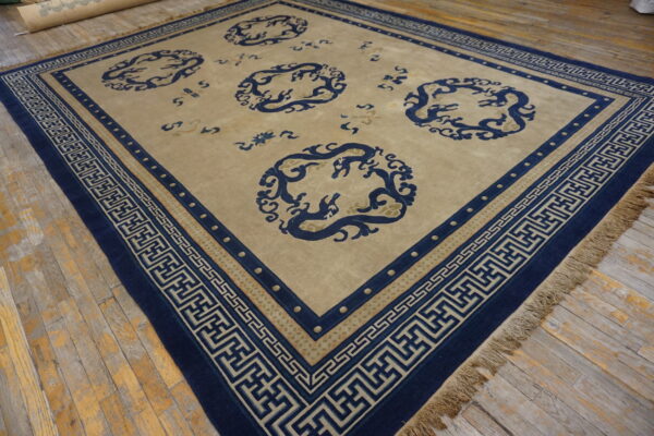 Tan rug featuring navy blue circular mythological motifs and greek key borders on weathered wood floorboards.