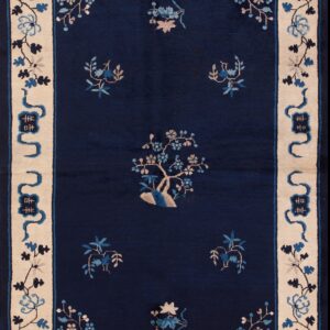 Medium-pile navy rug with scattered blue floral motifs and a wide beige pictorial border on distressed wood planks.