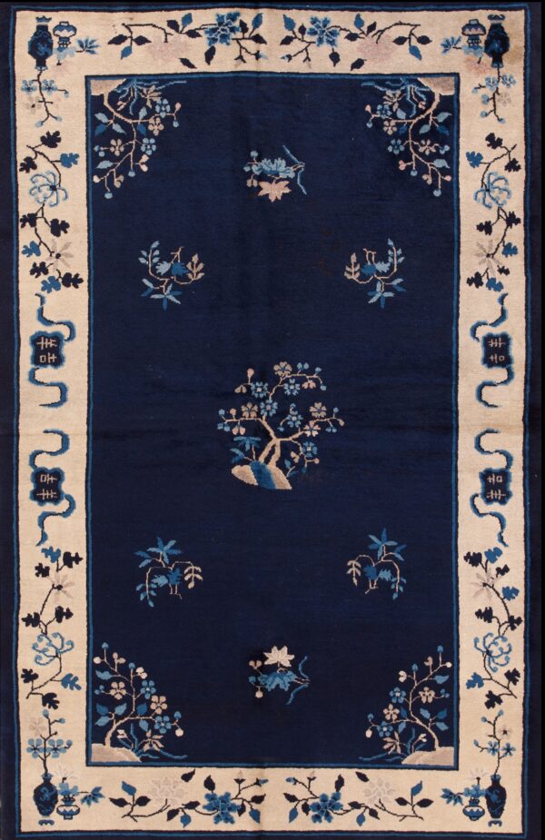 Medium-pile navy rug with scattered blue floral motifs and a wide beige pictorial border on distressed wood planks.