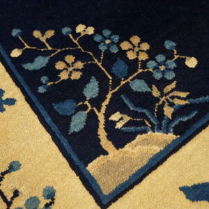 Close-up of a high-pile rug border featuring navy, gold, and light blue stylized floral motifs.