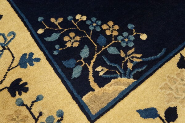 Close-up of a high-pile rug border featuring navy, gold, and light blue stylized floral motifs.
