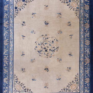 Cream rug with sparse floral sprays, a central medallion, and wide navy blue floral borders.