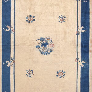 Light beige rug with a wide dark blue border and traditional blue and rust floral designs.