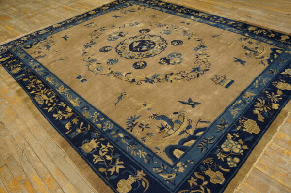 Tan rug with navy and light blue bird and floral motifs on distressed wood floors.