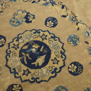 Low-pile rug with a beige field, detailed with navy, light blue, and cream floral medallions.