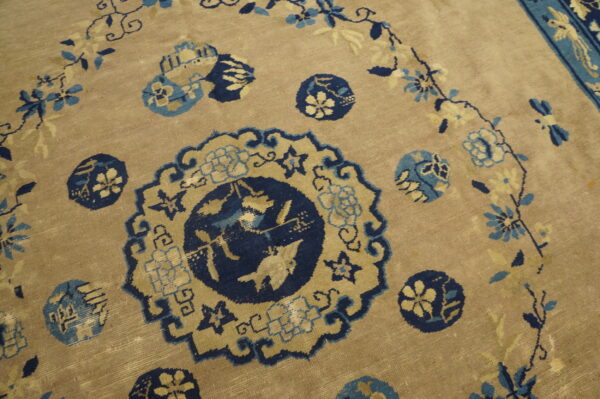 Low-pile rug with a beige field, detailed with navy, light blue, and cream floral medallions.