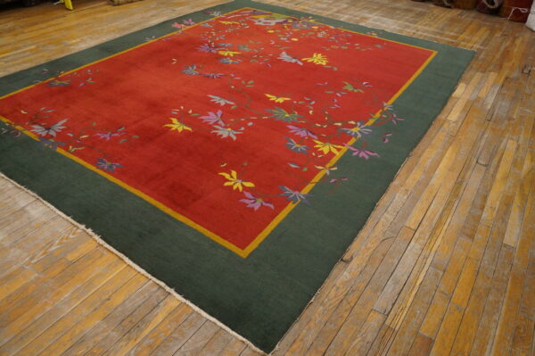 Red and green rug featuring scattered yellow, purple, and blue floral motifs on worn wooden planks.