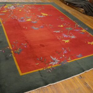 Red field rug with multicolored floral vines, a yellow accent stripe, and a wide dark green border on wood floors.