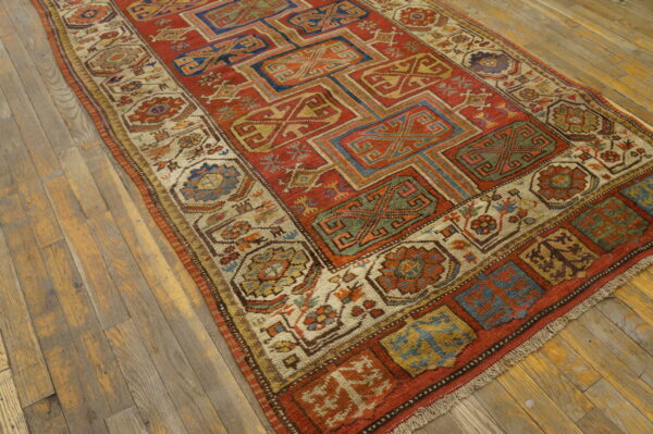 A geometric rug featuring rust red, blue, and gold motifs sits on rustic wood plank flooring.