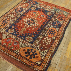Geometric rug in rust orange and navy blue on distressed natural wood plank flooring.