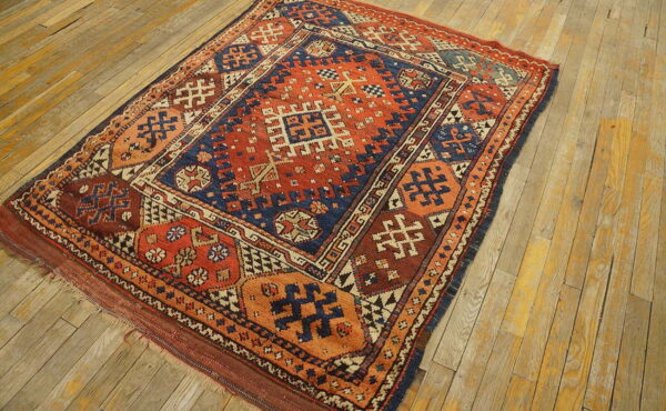 Geometric rug in rust orange and navy blue on distressed natural wood plank flooring.