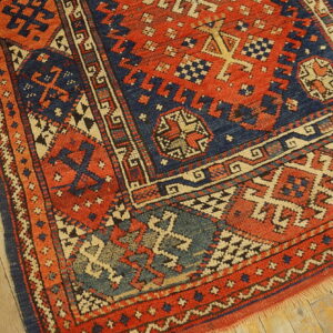Geometric rug in deep red and navy blue with cream accents on distressed wooden flooring.