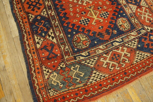 Geometric rug in deep red and navy blue with cream accents on distressed wooden flooring.