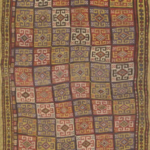 Geometric flatweave rug in a checkerboard pattern of red, purple, gold, and cream stylized squares.