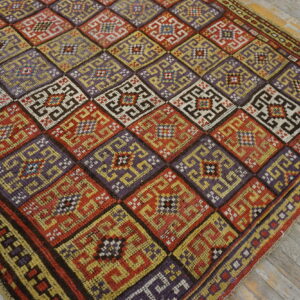 Vibrant geometric rug displaying large purple, red, and yellow squares over rustic wood planks.