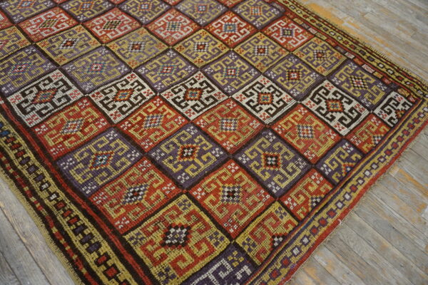 Vibrant geometric rug displaying large purple, red, and yellow squares over rustic wood planks.