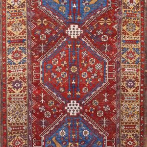 Geometric runner rug with a deep red field and repeating central blue, gold, and white medallion pattern.