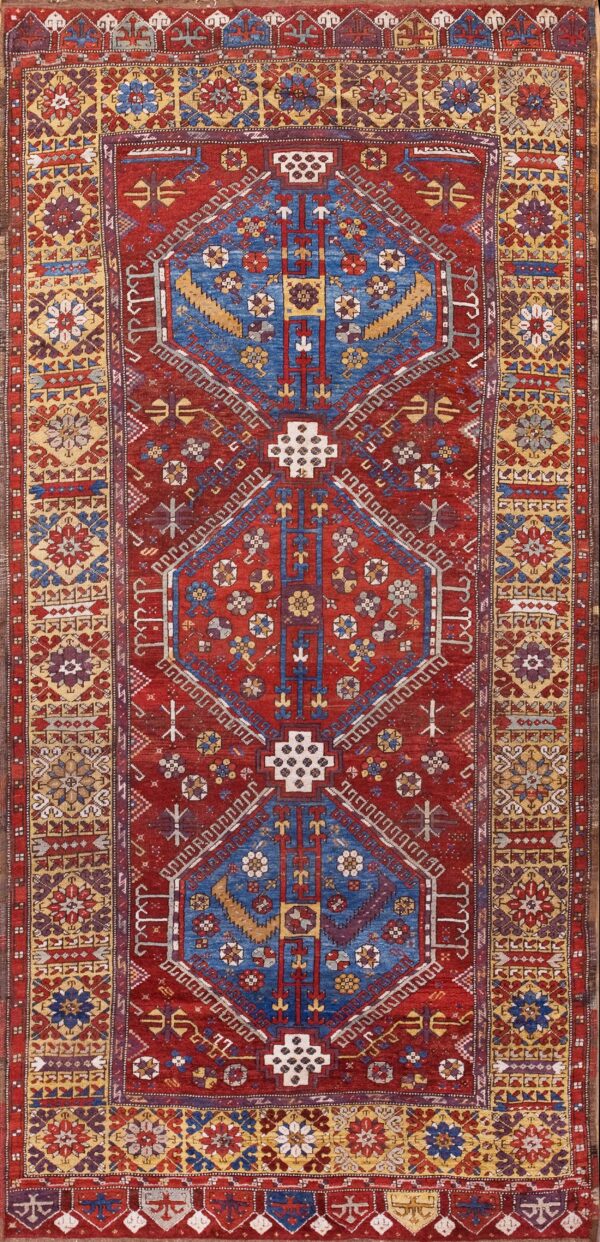 Geometric runner rug with a deep red field and repeating central blue, gold, and white medallion pattern.