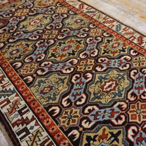 Red, blue, tan, and black geometric runner rug displayed on distressed light wood planks.