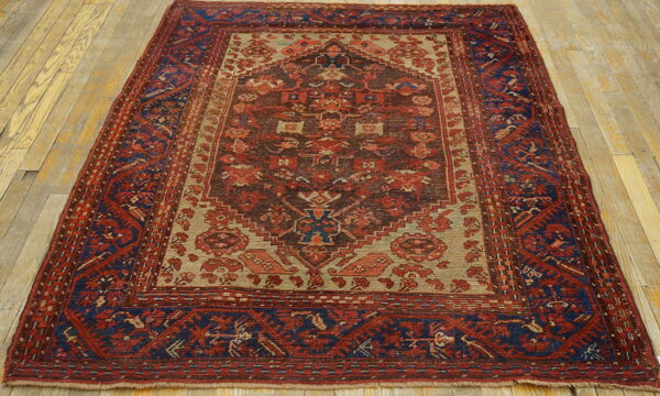 Red, navy, and tan tribal rug with a geometric medallion centered on light wood plank flooring.