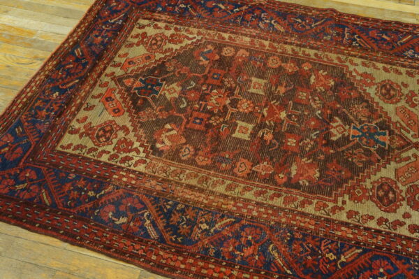Traditional rug featuring red, brown, tan, and dark blue geometric patterns on light wood planks.