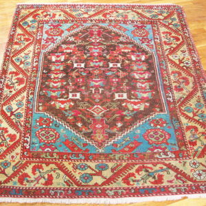 Geometric medallion rug in red, brown, teal, and gold on a polished hardwood floor.