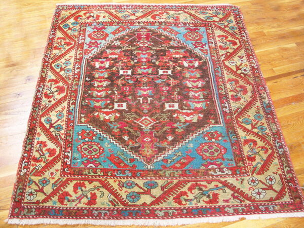 Geometric medallion rug in red, brown, teal, and gold on a polished hardwood floor.