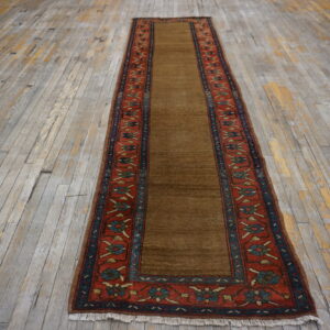Saddle brown runner rug with red and blue floral borders rests on rustic gray wood planks.