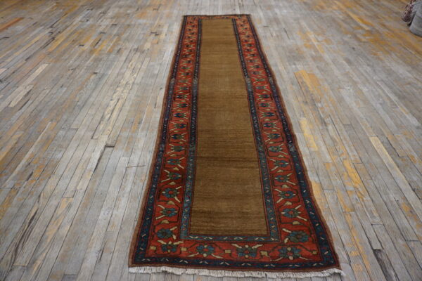 Saddle brown runner rug with red and blue floral borders rests on rustic gray wood planks.