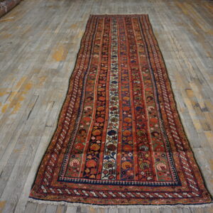 Red and blue runner rug with striped floral motifs displayed on distressed gray wood planks.