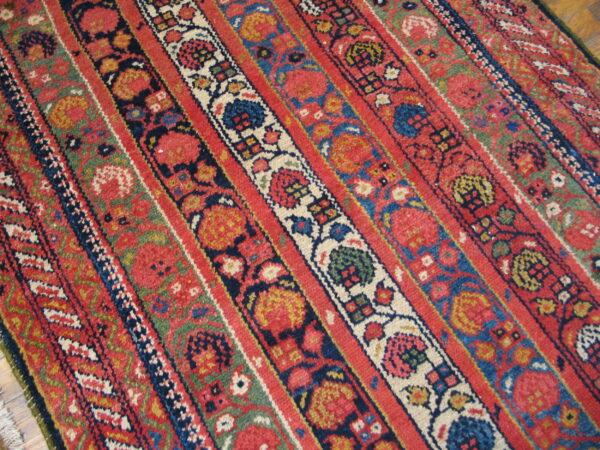 Low-pile rug with colorful red, blue, green, and cream floral and geometric striped patterns.