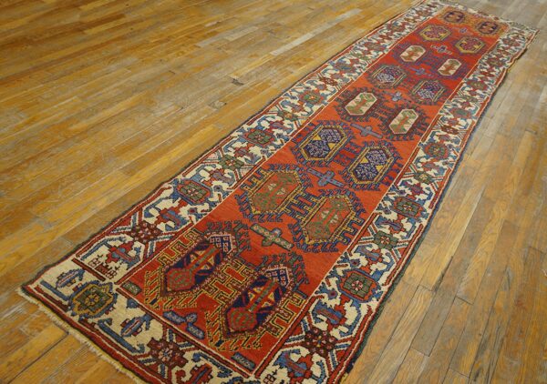 Rust-orange runner featuring complex geometric patterns in blue and cream on wide, distressed wood planks.