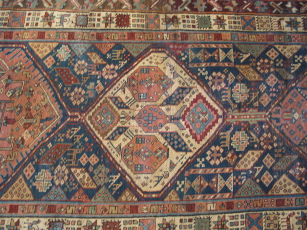 Close-up of a tightly woven rug showing geometric diamond motifs in navy, coral, cream, and brown.