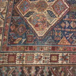 Detailed view of a navy blue and beige rug with complex geometric motifs and multiple borders.