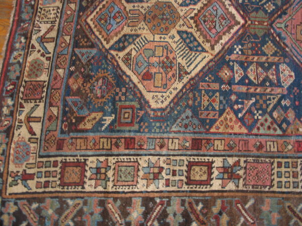 Detailed view of a navy blue and beige rug with complex geometric motifs and multiple borders.