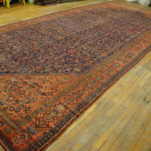 Long rug with an intricate blue and rust geometric design laid across a plank wood floor.
