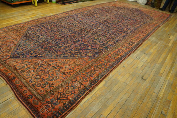 Long rug with an intricate blue and rust geometric design laid across a plank wood floor.