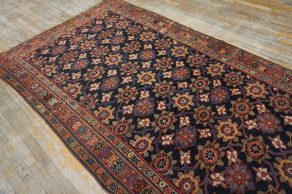Ornate dark blue and red patterned rug with a complex border resting on light plank wood flooring.