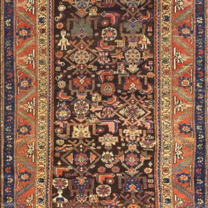 Dark brown runner rug with densely packed multicolored geometric figures bordered by broad rust red bands.