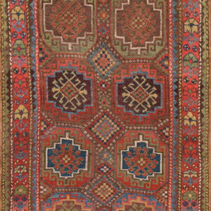 Low-pile geometric rug featuring repeating red, blue, green, and brown medallions with intricate borders.