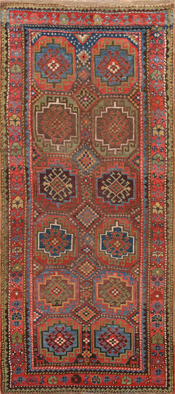 Low-pile geometric rug featuring repeating red, blue, green, and brown medallions with intricate borders.