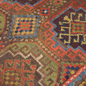Detailed view of a multicolored geometric rug pattern featuring red, blue, green, yellow, and deep brown.